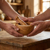 Two hands lifting the Alba Olive Wood Mortar and Pestle off a wooden table