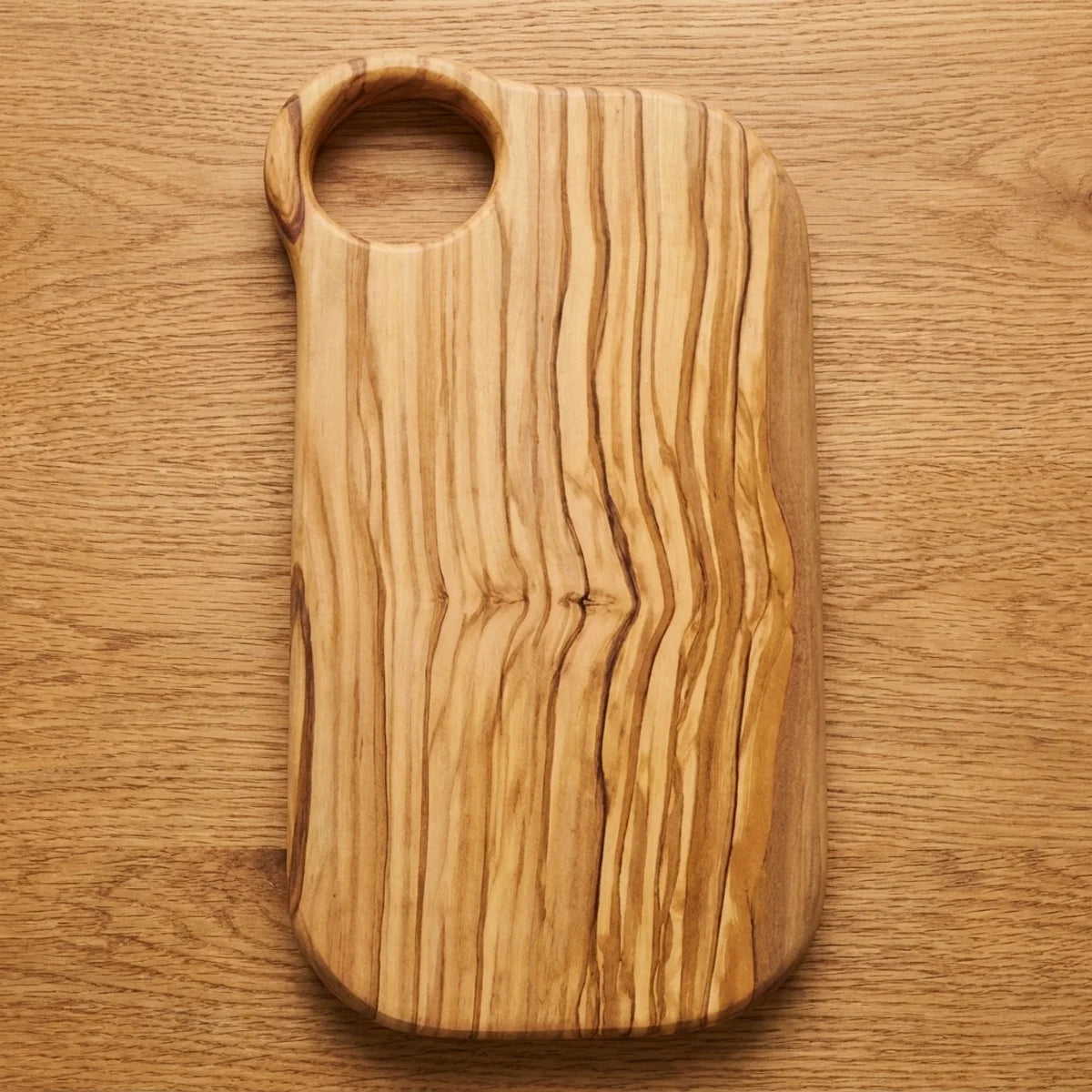 The Alba Olive Wood Board with Grip Hole seen from above, the full grain readable