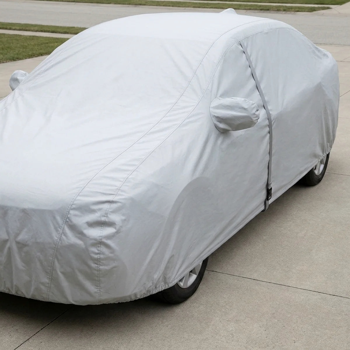 The car cover fitted over a sedan, whole car visible from bumper to bumper