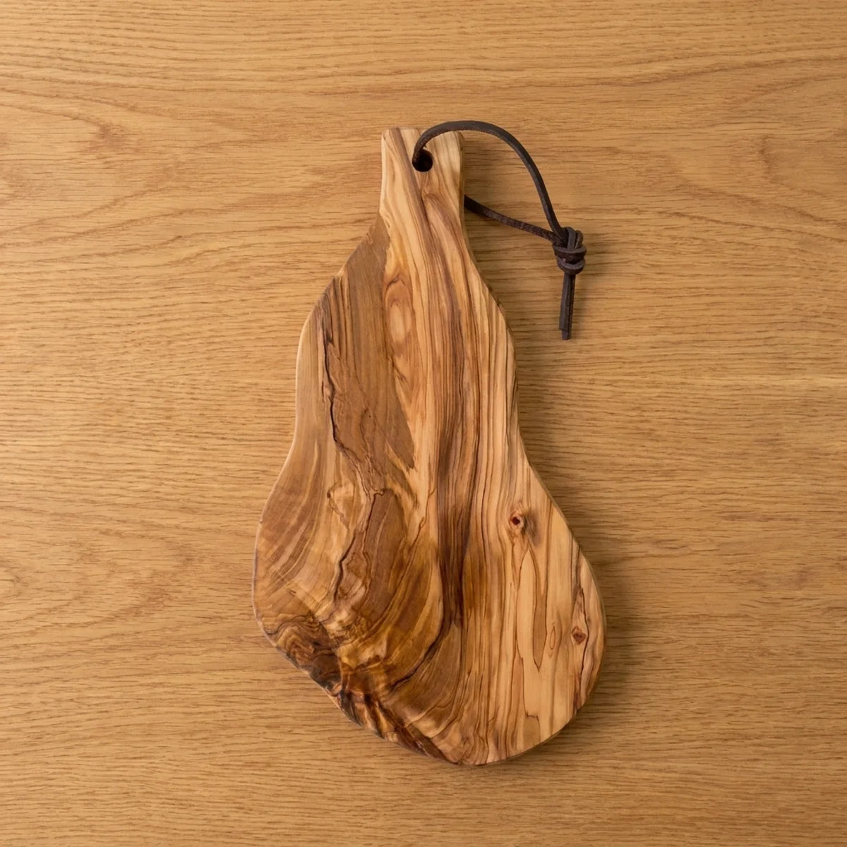 The Alba Olive Wood Board with Leather Loop seen from above, the full grain readable