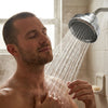 A man showering under the filtered shower head mounted on the wall arm