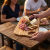 The Alba Olive Wood Board with Grip Hole in use on a dining table