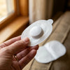 Close-up of one gel pad held between two fingers, the pod attached, the gel surface catching the light