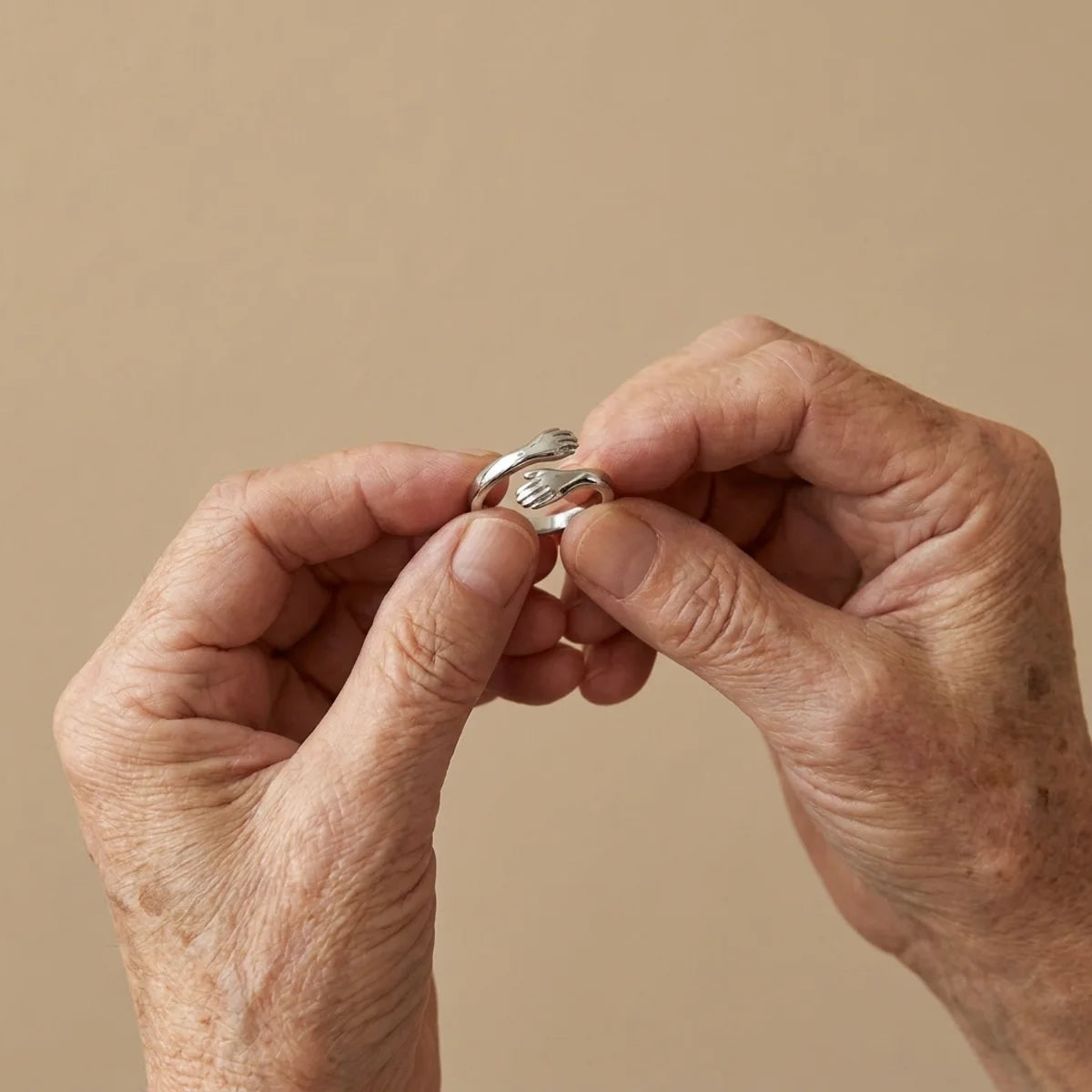 The Hug Ring held in two older hands