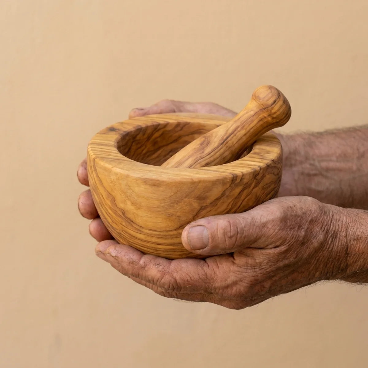 The Alba Olive Wood Mortar and Pestle held in two hands, showing its size