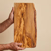The Alba Live-Edge Olive Wood Slab held in two hands, showing its size