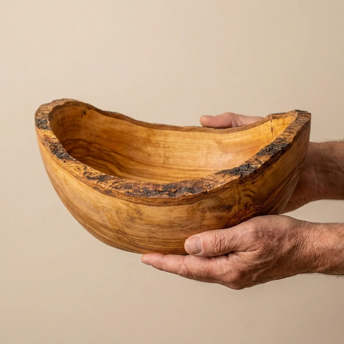 The olive wood bowl held in two hands, showing its size