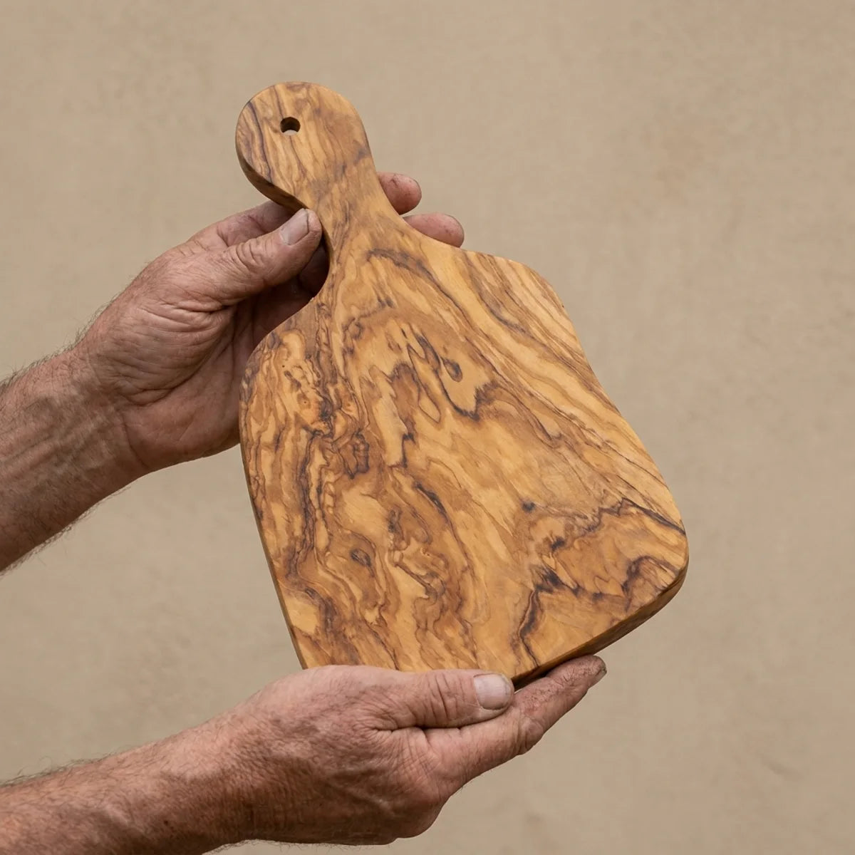 The Alba Olive Wood Paddle Board held in two hands, showing its size