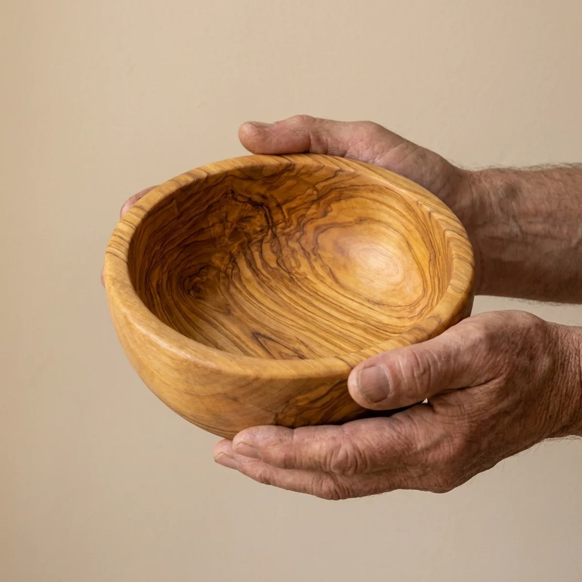 The Alba Olive Wood Salad Bowl held in two hands, showing its size