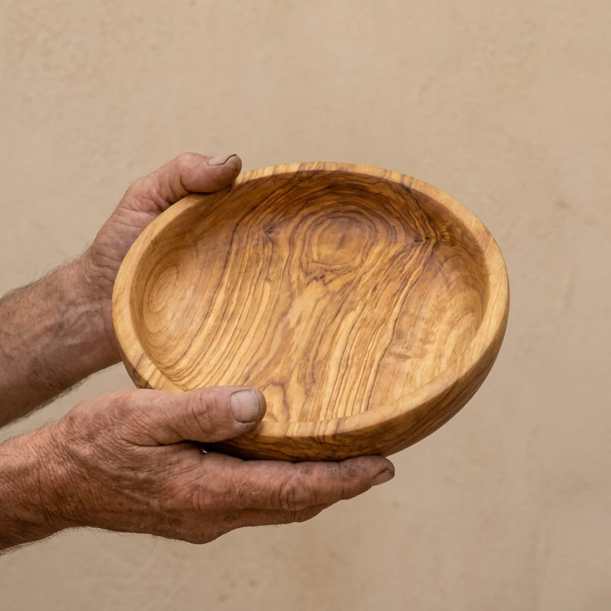 The Alba Olive Wood Bread Bowl held in two hands, showing its size