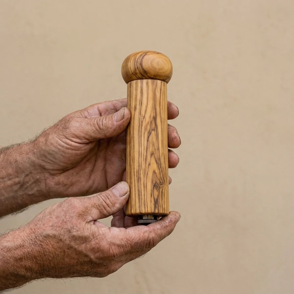 The Alba Olive Wood Pepper Mill held in two hands, showing its size
