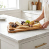 The Alba Olive Wood Board with Grip Hole in use on a kitchen island