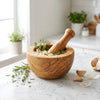 The Alba Olive Wood Mortar and Pestle in use on a kitchen island