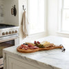 The Alba Olive Wood Board with Leather Loop in use on a kitchen island