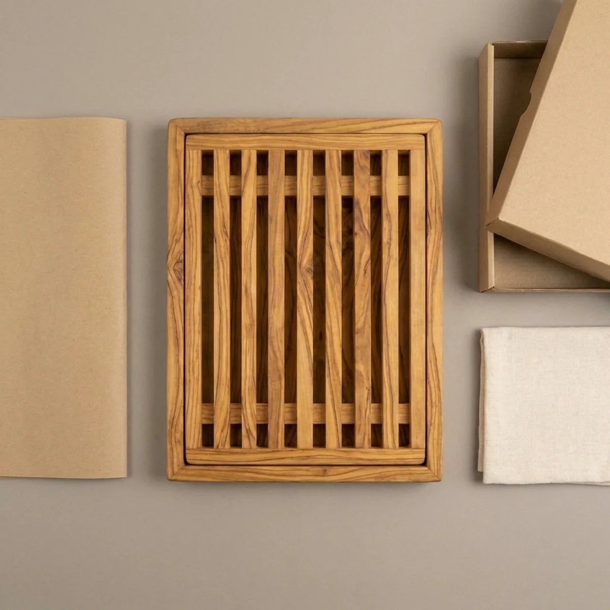 The Alba Olive Wood Bread Board with Crumb Tray with its kraft wrapping and plain shipping box