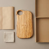 The Alba Olive Wood Board with Grip Hole with its kraft wrapping and plain shipping box