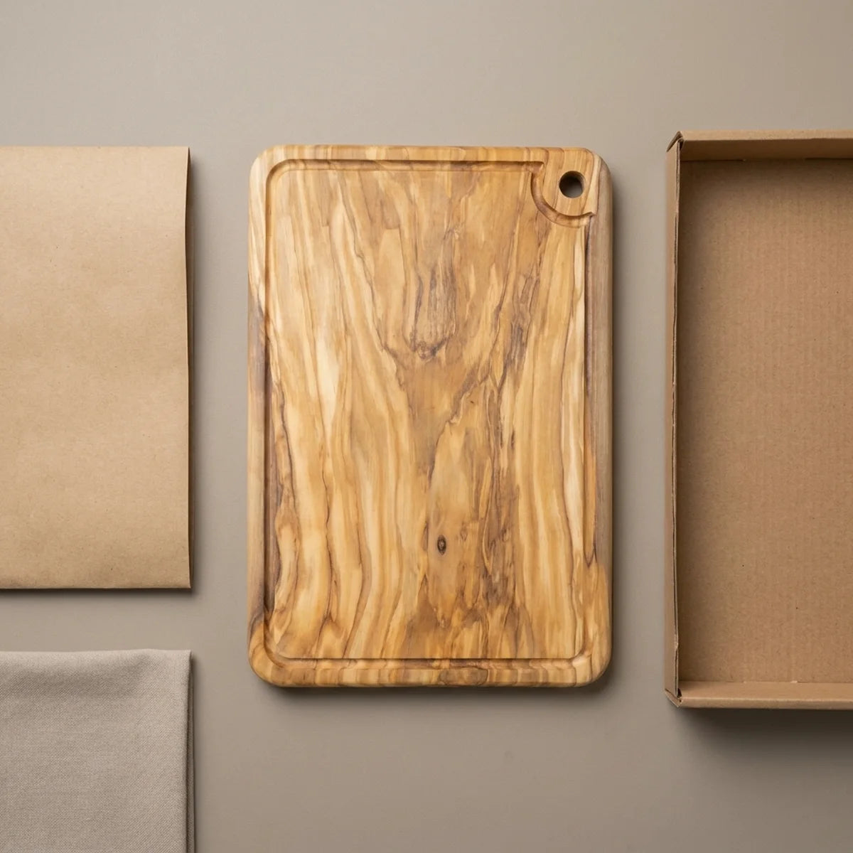 The Alba Olive Wood Carving Board with Juice Groove with its kraft wrapping and plain shipping box