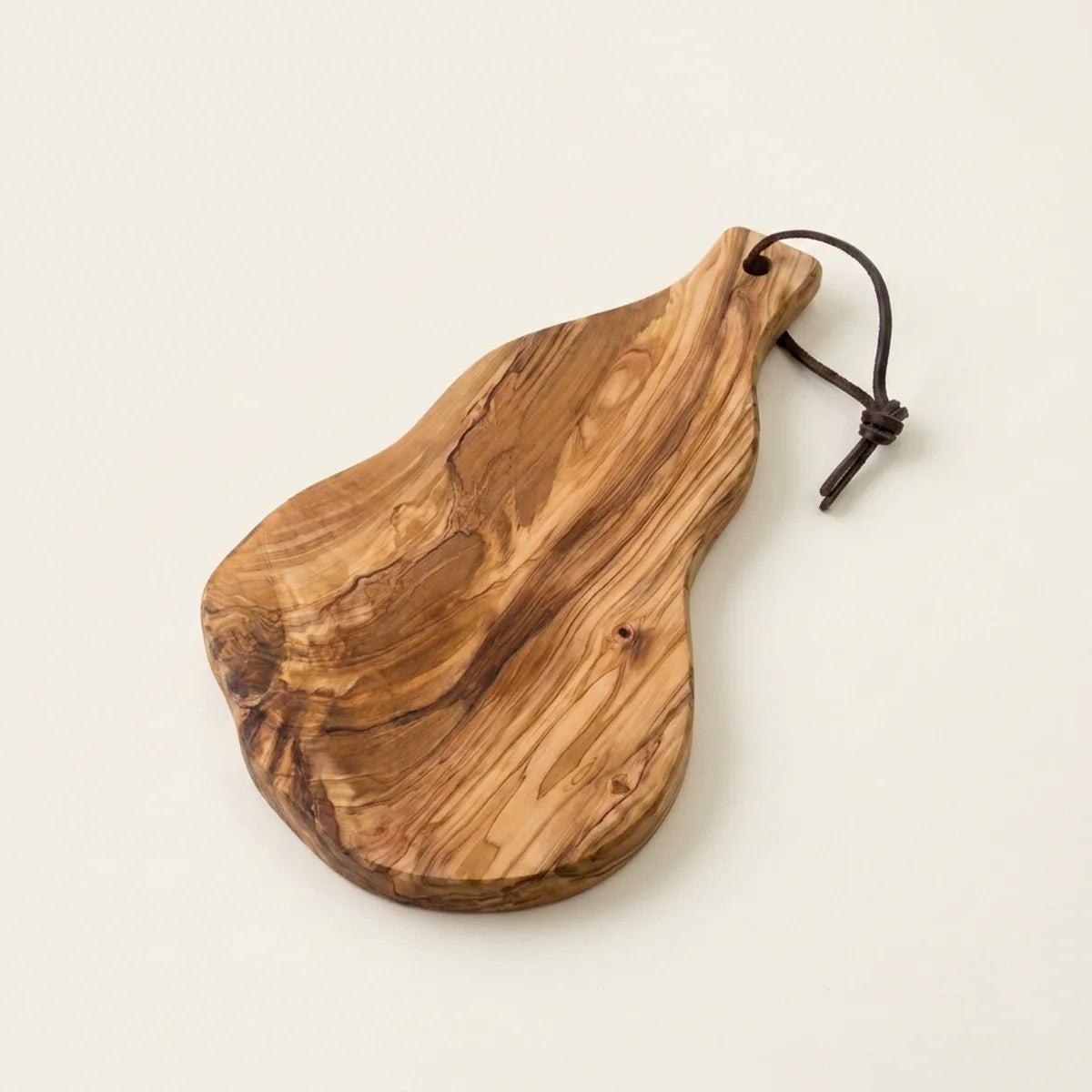 The Alba Olive Wood Board with Leather Loop alone on a plain background